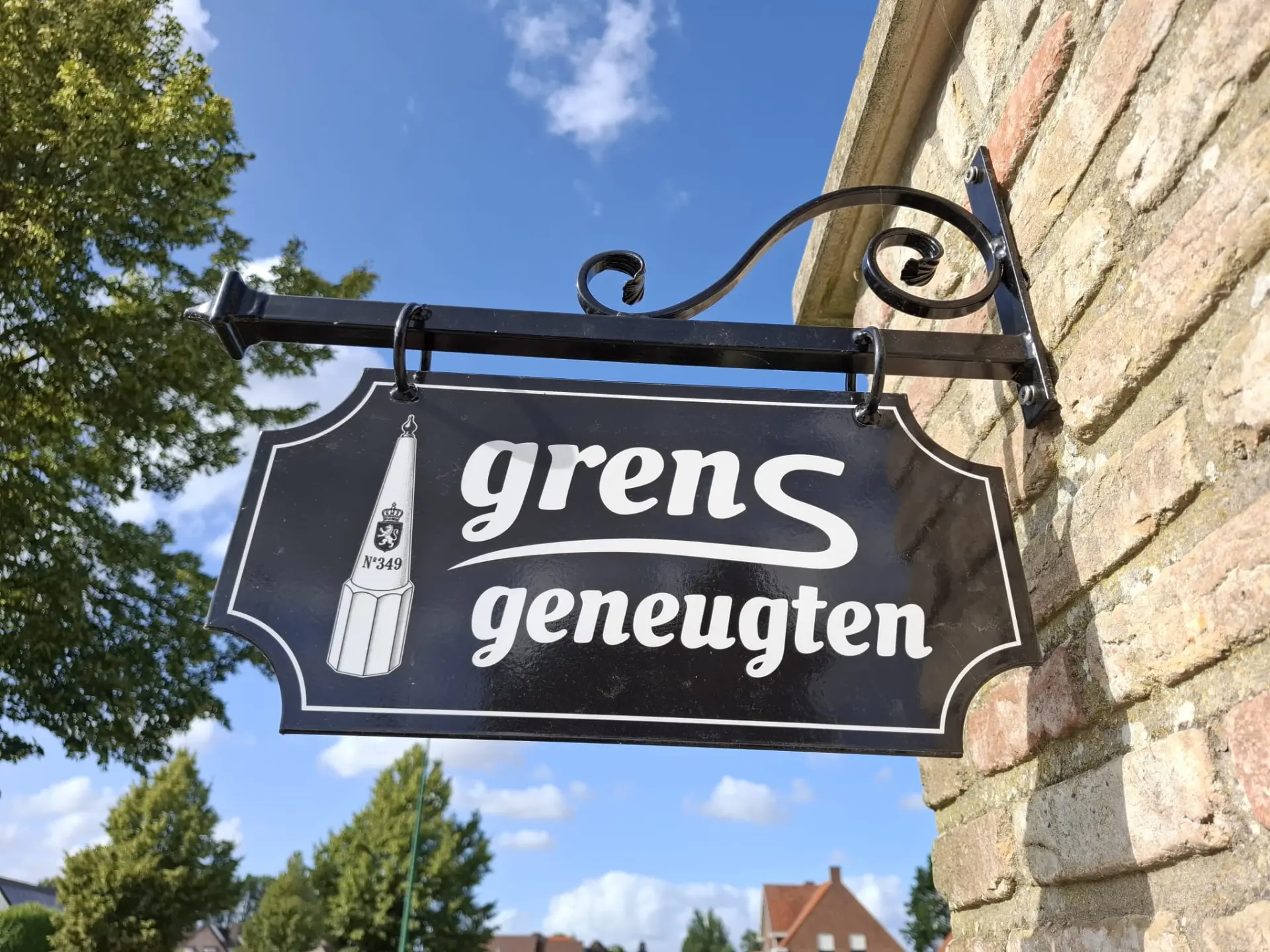 Het smeedijzeren naambord 'grensgeneugten' aan de bakstenen muur
