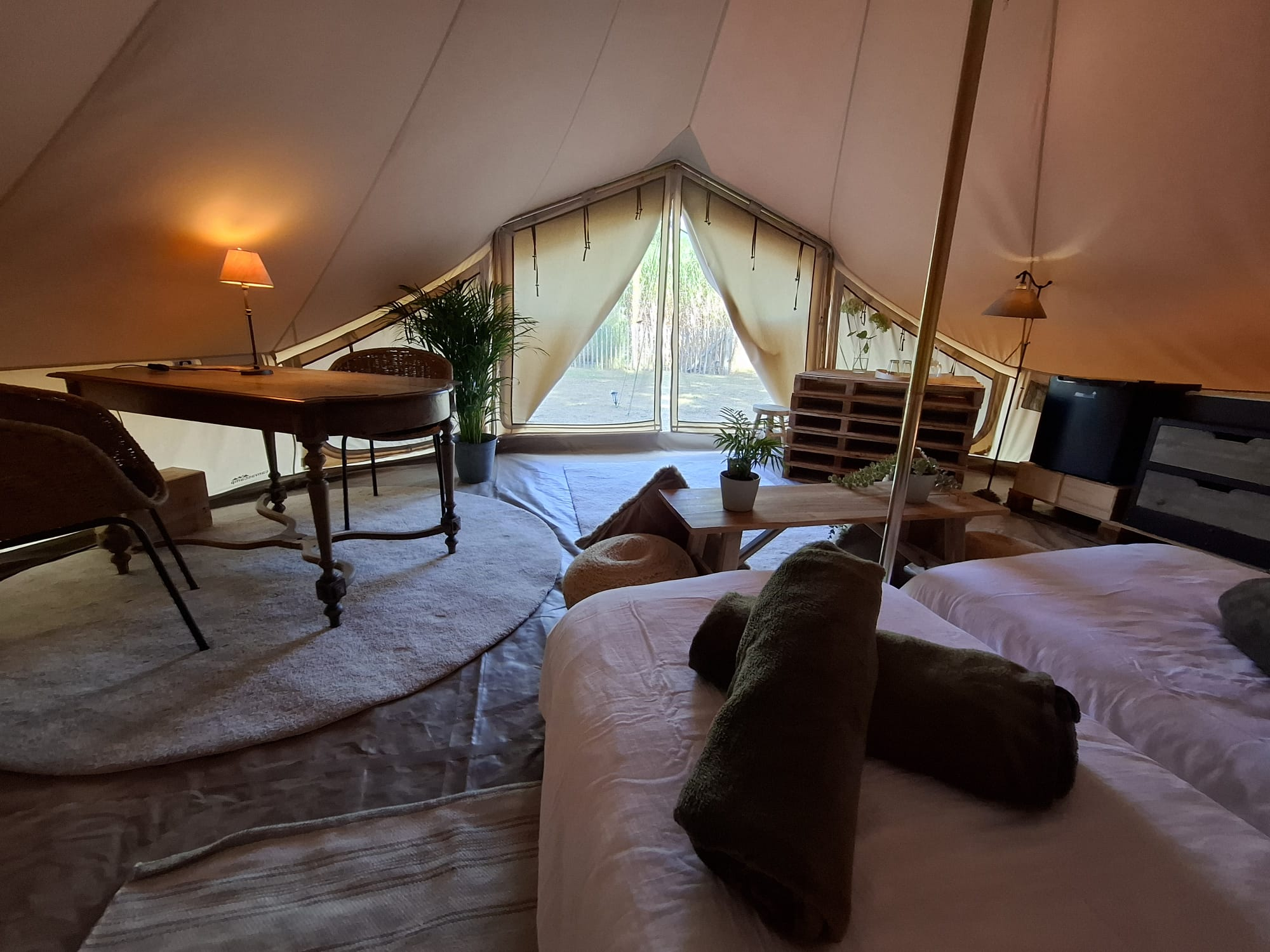 Zicht vanuit de glampingtent door de open tentflappen op de weide