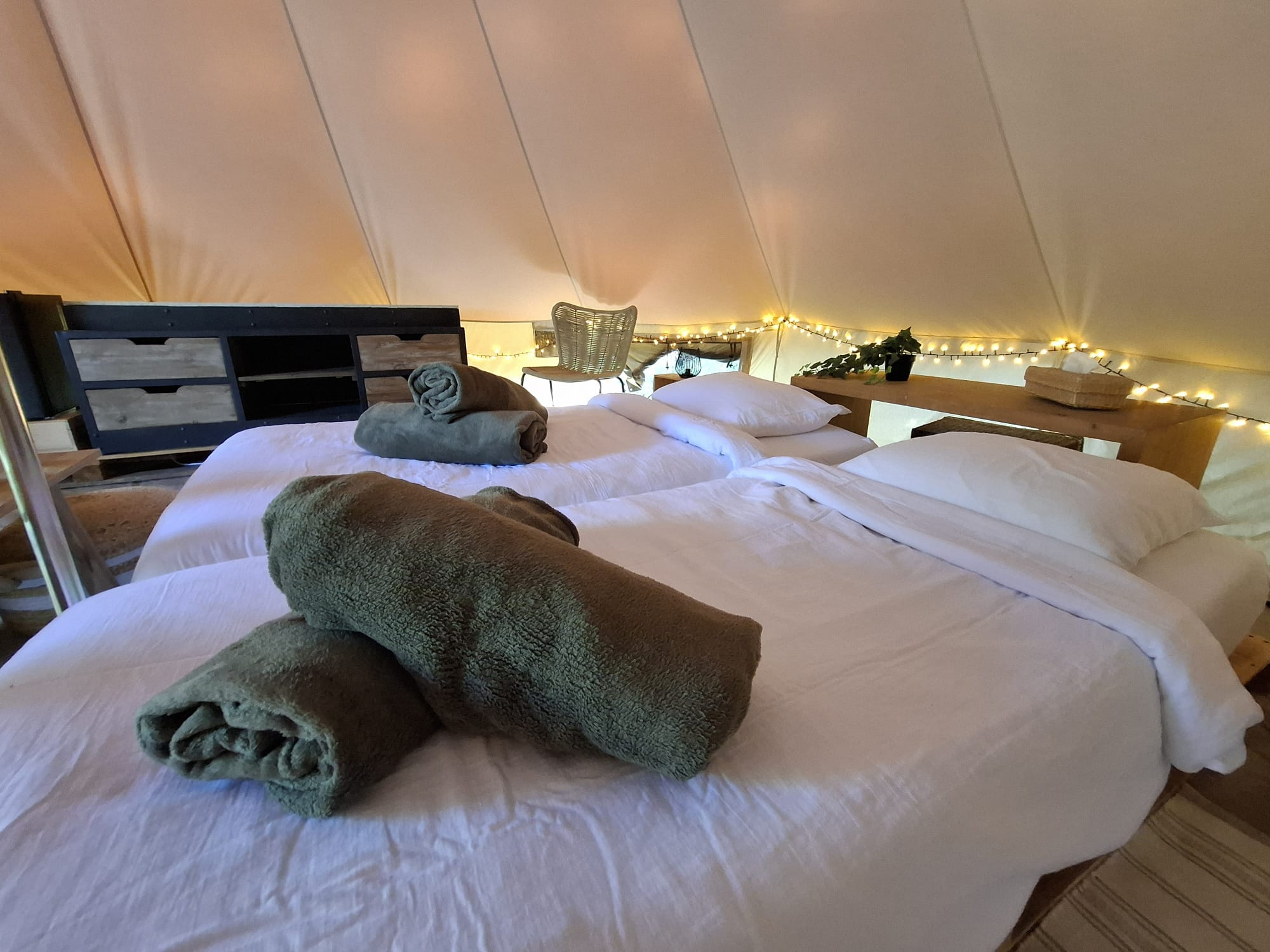 Twee opgemaakte bedden met handdoeken in de glampingtent