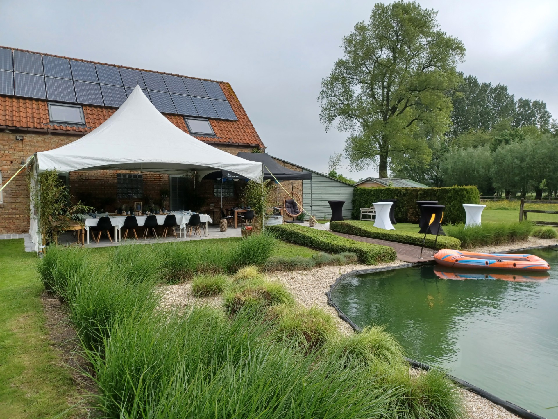 Witte pagodetent met feestelijk gedekte tafel naast de zwemvijver